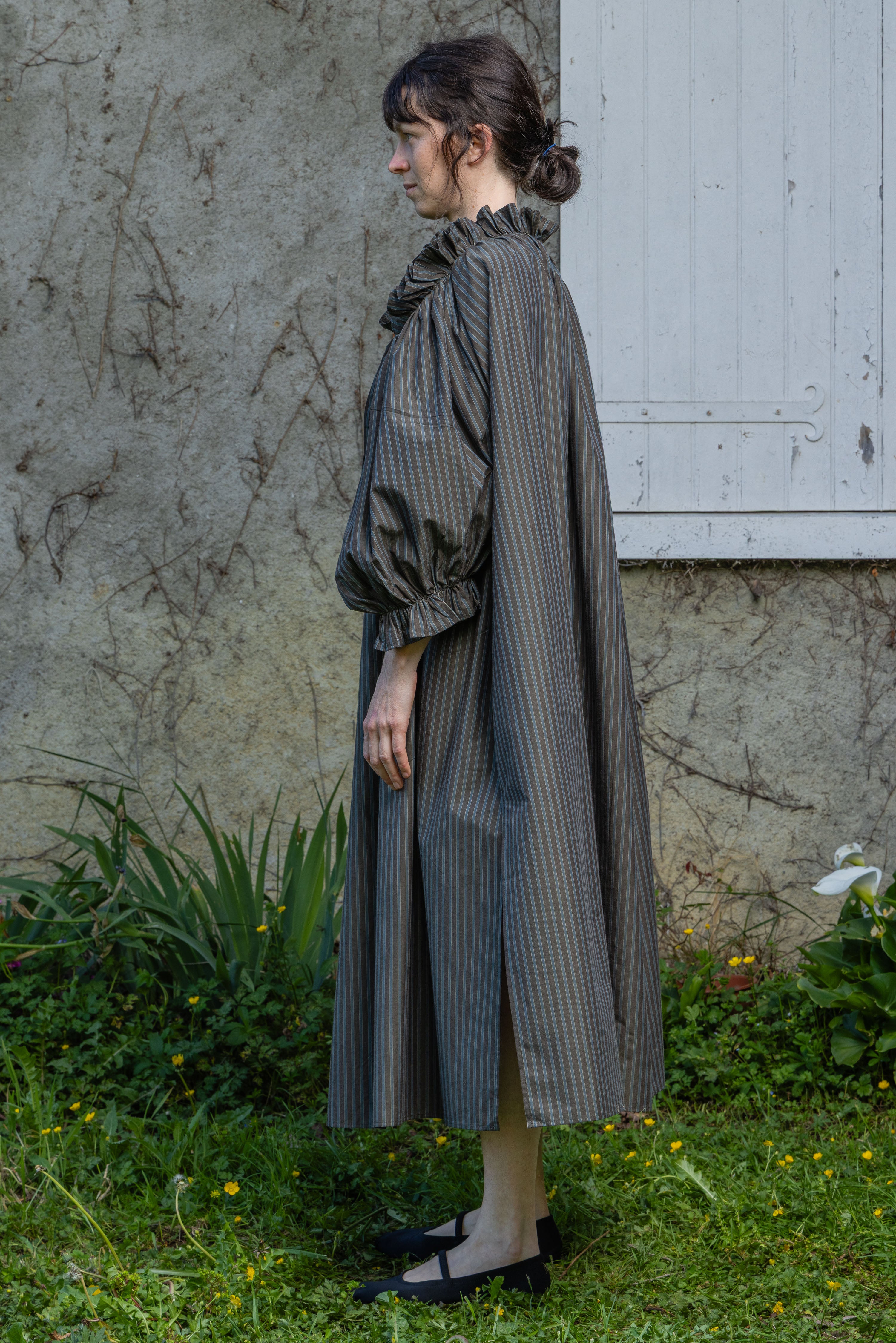 Olive striped midi dress with ruffled high collar and long puff sleeves, side view.