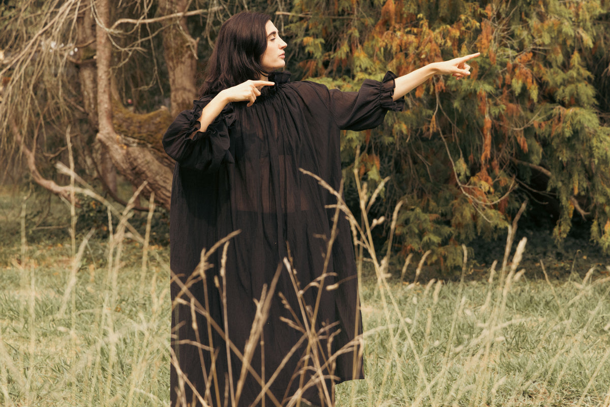 Black maxi dress with ruffled neckline, loose fit, and full-length billowy sleeves